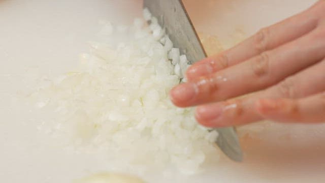 흰 도마 위에서 칼로 양파를 자르기