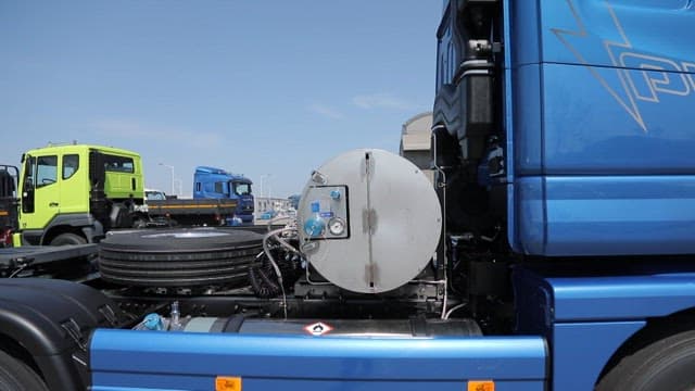 맑은 하늘 아래 창고 근처에 주차된 LNG 트럭