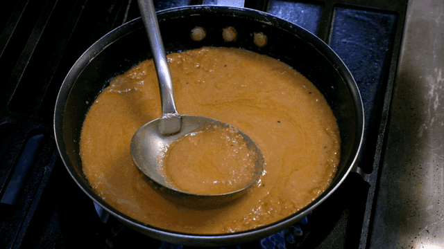 Ladle for stirring sauce in pan on stove