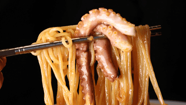 Chopsticks picking up octopus and Jjamppong noodles