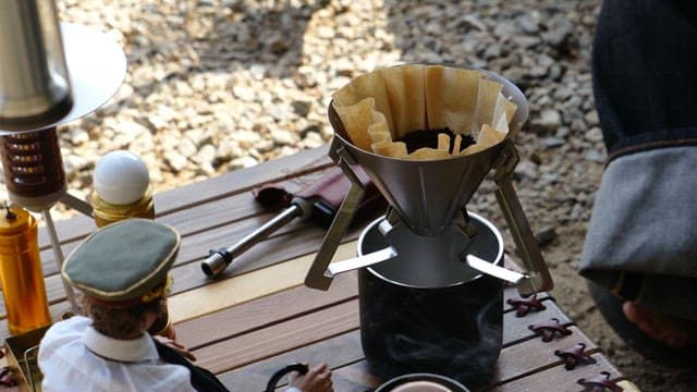 Coffee made with a portable dripper for outdoor camping on a wooden table