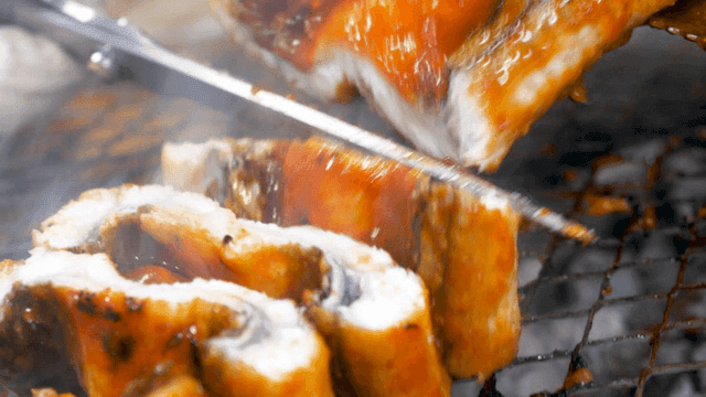 양념 장어를 가위로 잡고 있는 장갑 낀 손