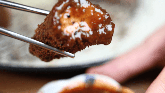 Piece of fried black pork cutlet dipped in sauce