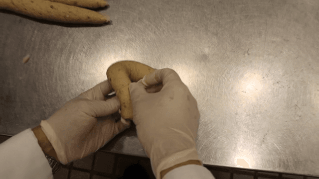 Hands shaping dough on a metal table