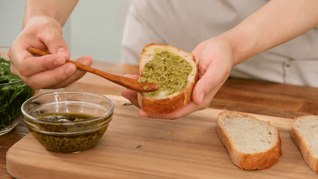 Spoon basil pesto onto bread