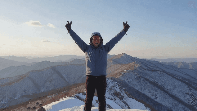 A person celebrating on a snowy mountain peak