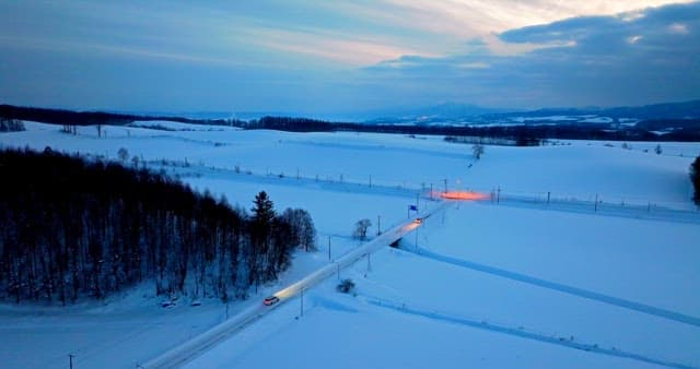 Twilight over snowy countryside with passing car