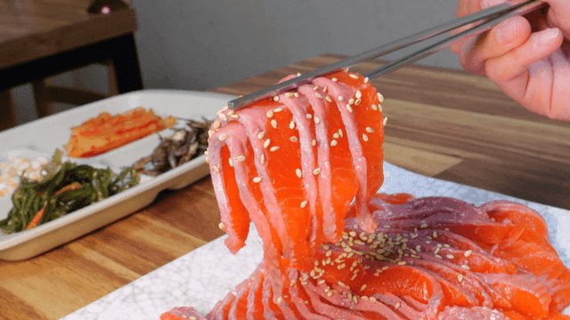 Fresh trout sashimi lifted with chopsticks