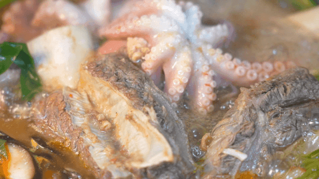 Sight of rich broth live octopus and short rib hot pot boiling