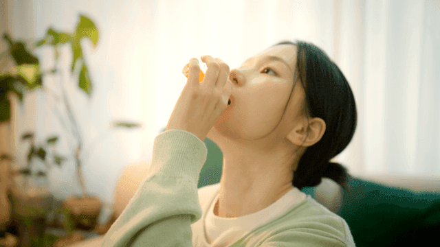 Woman taking liquid vitamin supplement in living room