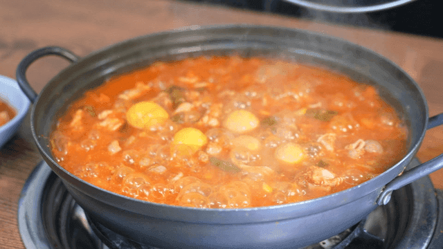 Spicy chicken offal stew boiling in pot with open lid