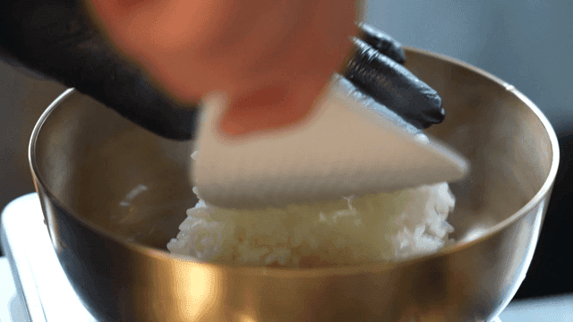 Rice being placed into a brass bowl