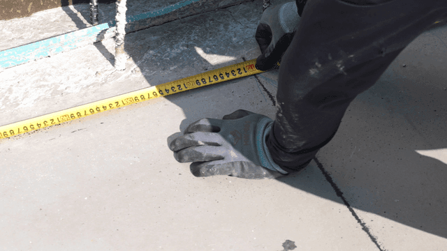 Measuring concrete floor with tape measure