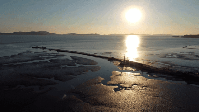 Sunset over a tranquil sea with a pier