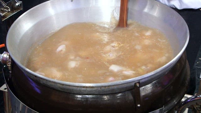 Stirring chickens boiled in a large pot with paddle