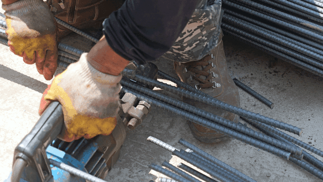 Worker cutting steel bars with a machine