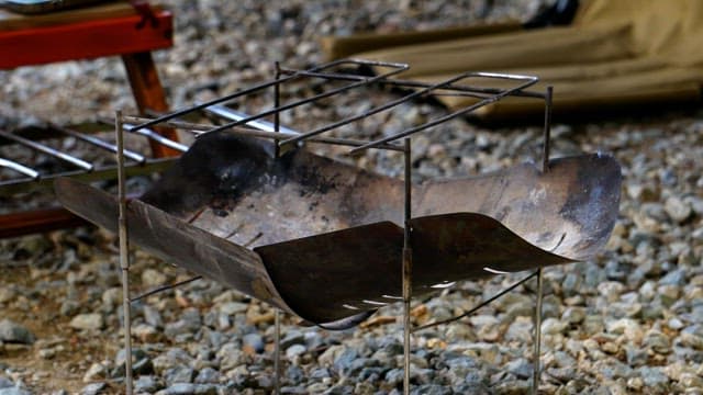 Setting up a portable grill outdoors on a gravel surface