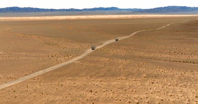 Vans traveling through a vast desert landscape