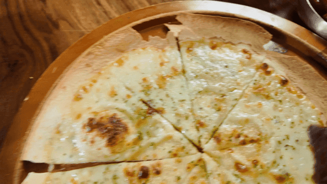 Grilled beef short ribs and cheese pizza on table