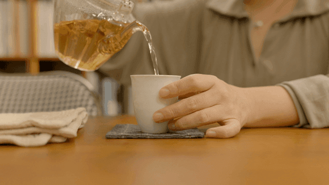 Pouring tea into a cup on a wooden table