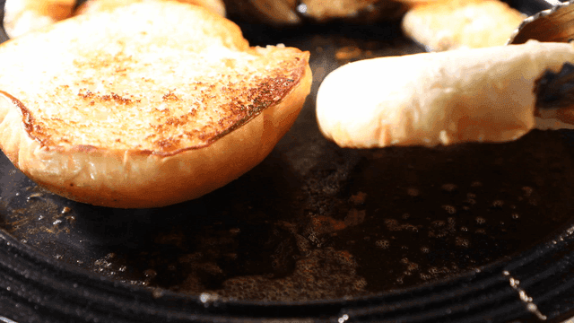Shrimp and vegetables on bun on hot iron plate