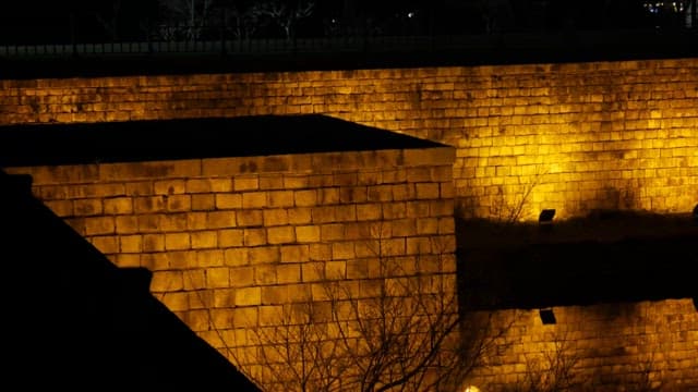 Night view of an illuminated ancient stone wall reflected in water