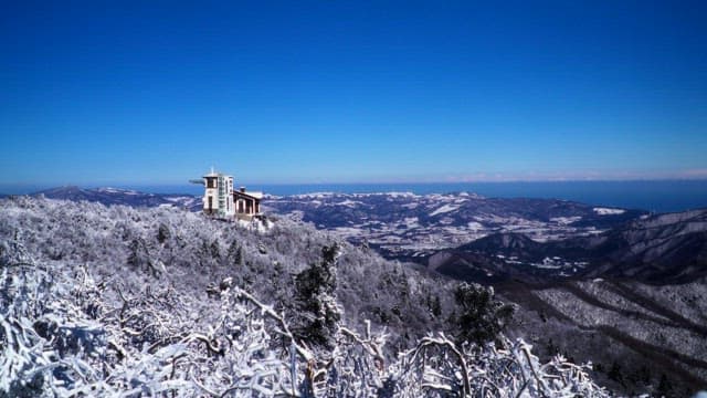 Building and valleys on top of snow-covered mountains under clear blue skies