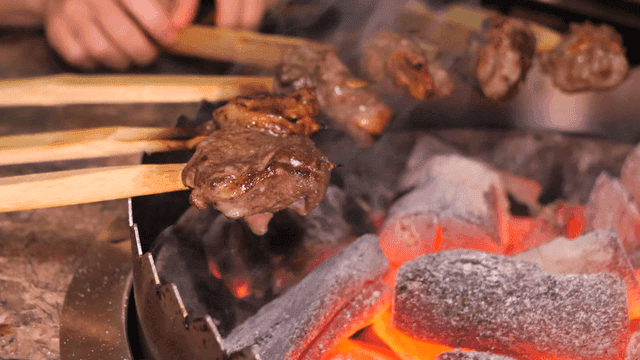 Primitive skewers grilling meat over hot charcoal
