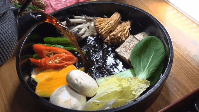 Pouring broth into a pot with vegetables