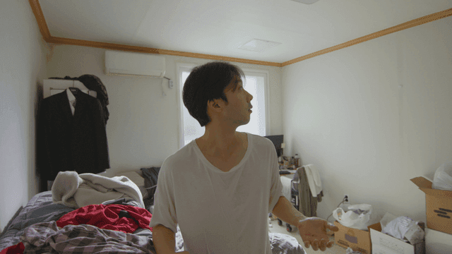 어수선한 방에서 위를 바라보는 젊은 남성