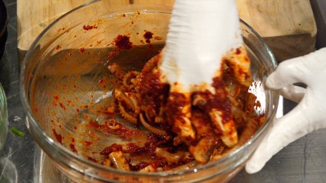 유리 그릇에서 매운 양념과 낙지를 섞는 모습