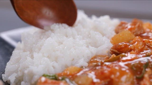 숟가락으로 비벼지는 돼지고기와 무볶음이 들어간 덮밥