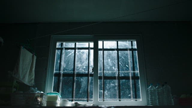 Man sitting under a barred window in prison