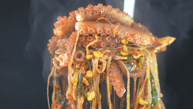 Ladle scooping out spicy stir-fried live octopus with vegetables