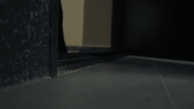 Door slightly opening in a dim hallway