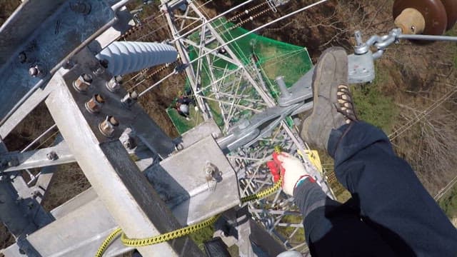 Worker connecting safety cables to maintain transmission towers