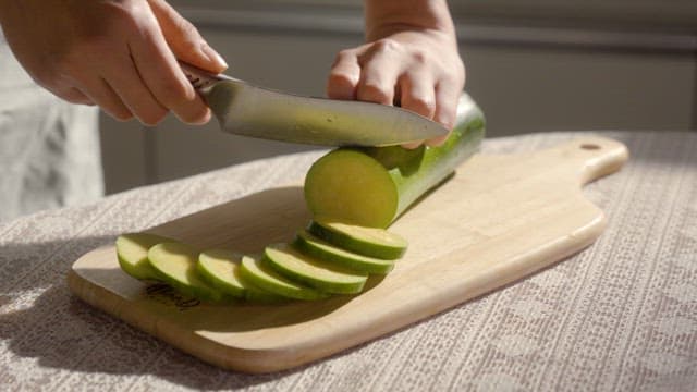 Slicing a zucchini on a wooden board