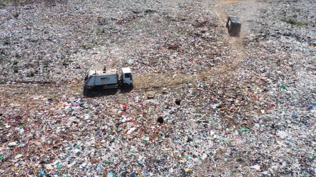 Truck driving through a vast landfill during the day