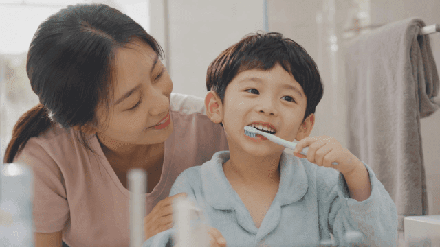 A mother helping her child brush teeth