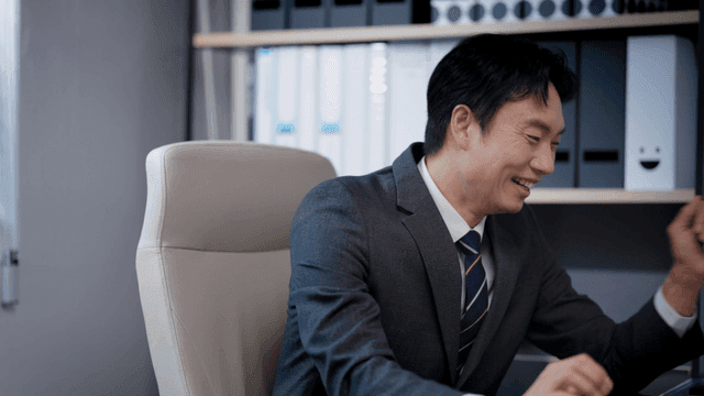 책상에 앉아 환호하는 사업가