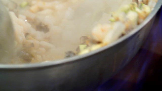 뜨거운 팬에서 볶아지는 우렁이와 다진 채소들