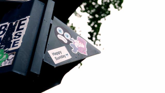 Stickers on a street sign with trees