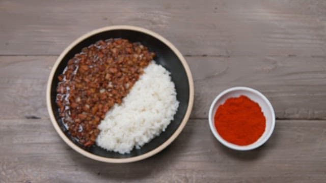 Appetizing black bean sauce with rice with minced meat and onions and red pepepr on wooden table