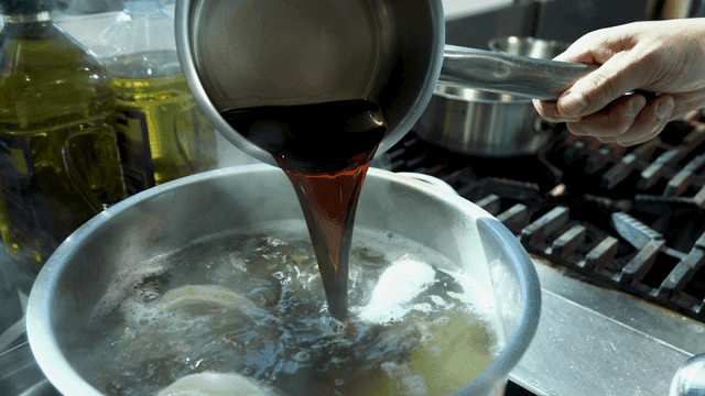 Soy sauce poured into pot of boiling broth