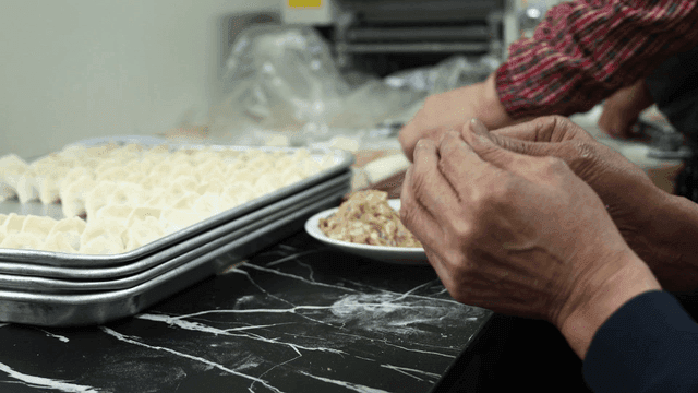 Hands of people making dumplings in kitchen