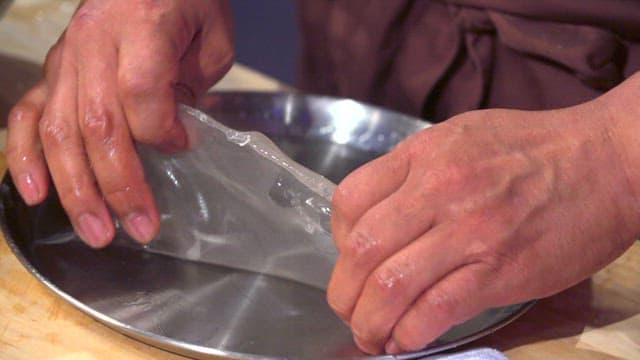 Chef removing cooked starch batter from a tray