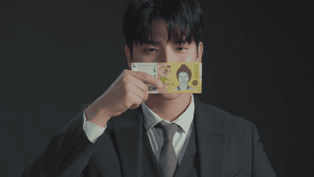 돈으로 입을 가린 채 웃는 남자