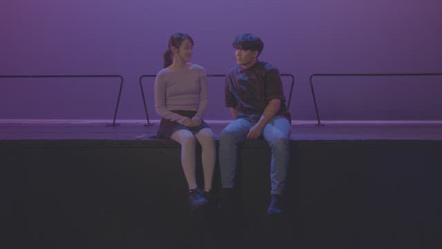 Couple sitting on a stage under purple lighting