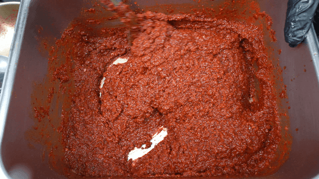 Mixing gochujang on tray by ladle