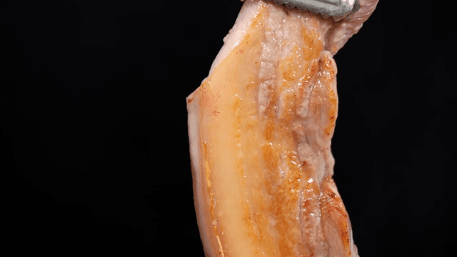 Grilled pork belly lifted with tongs